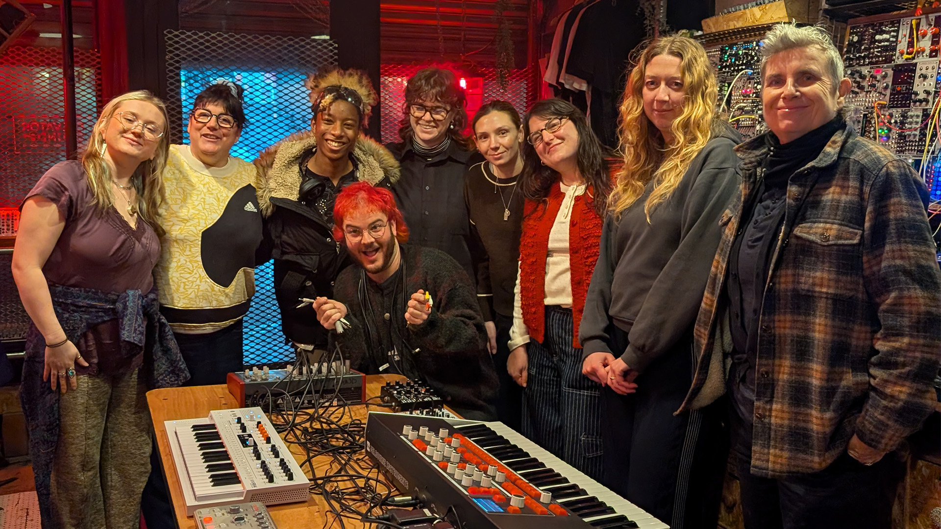 The Saffron team and a group of students at a Saffron workshop standing in front of music technology equipment.