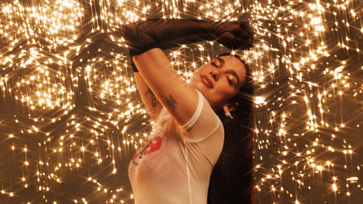 Dua Lipa posing against a glittery backdrop