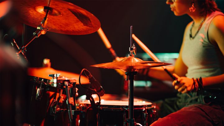 Female drummer performing live on stage with drum set