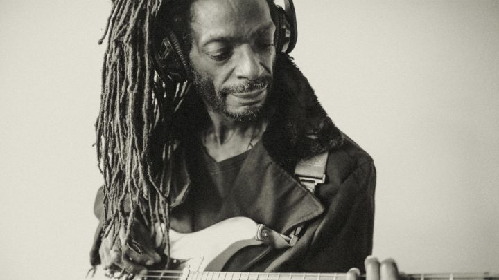 Reggae musician playing the guitar and wearing headphones